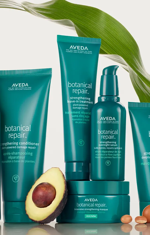 Aveda Botanical Repair hair care products displayed with an avocado and a green leaf in the background, perfect for enhancing your hair style and keeping it healthy.